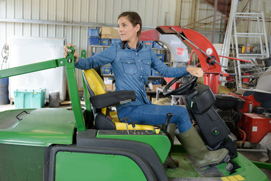 portrait of smiling young female mechanic inspecting tractor