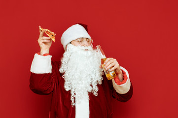 Joyful Santa Claus with a piece of pizza and a bottle of beer in his hand stands on a red background with his eyes closed, smiling and having fun. Funny man in santa costume having fun, isolated.