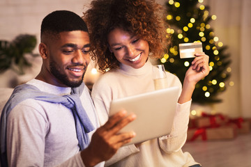 Christmas preparation. Happy black couple buying gifts online