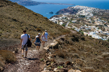 Fira Oia trail with hikers and the view of Oia from above - obrazy, fototapety, plakaty