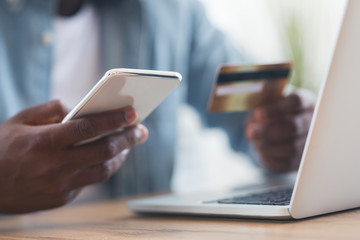 Unrecognizable black man using smartphone and credit card, shopping online