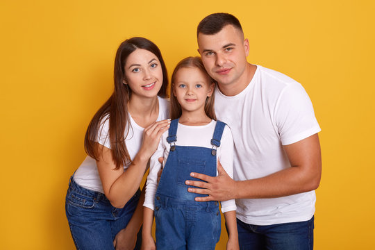 Portrait Of Happy Family Against Yellow Studio Background, Pose Smiling, Spending Time Together, Wearing Casuall Clothes, Having Positive Facial Expression. Deepdevotion And Relationship Concept.