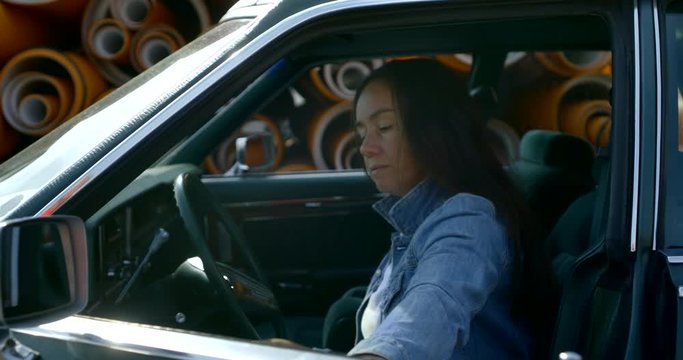 brunette woman is closing door of old rarity car sitting on driving-seat