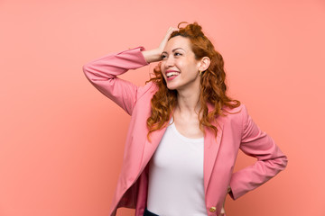 Naklejka premium Redhead woman in suit over isolated pink wall laughing