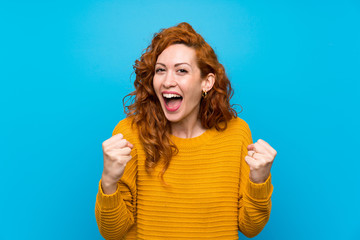 Redhead woman with yellow sweater celebrating a victory in winner position