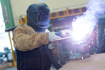 worker in protective mask using gas torch making large flame
