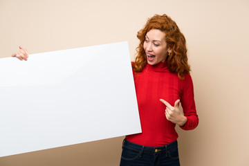Redhead woman with turtleneck sweater holding an empty white placard for insert a concept