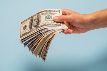 Woman hands counting dollar banknotes on blue background