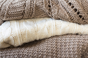 Stack of cozy knitted sweaters on a wooden table. Retro style. Warm concept. close up