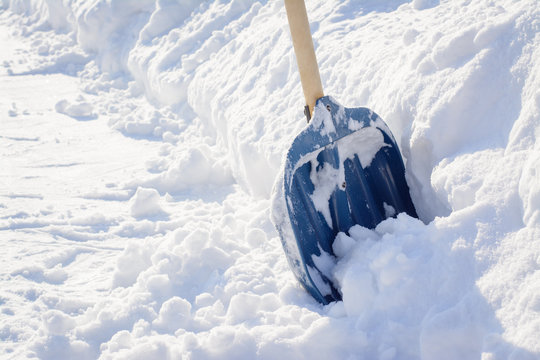 Cleaning snow after a snowstorm in winter. Snow shovel near a big snowdrift before removing snow in a sidewalk