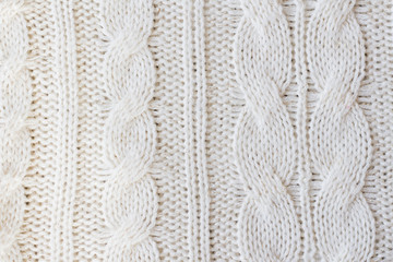White knitted carpet closeup. Textile texture off white background. Detailed warm yarn background. Knit cashmere beige wool. Natural woolen fabric, sweater fragment.