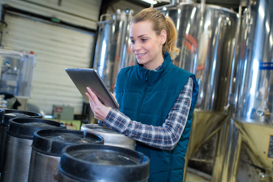 woman working at a brewery using a tablet - Powered by Adobe