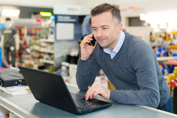salesman talking on smartphone while looking at laptop