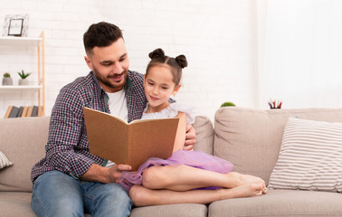 Caring daddy reading book to his cute daughter