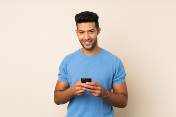 Young handsome man over isolated background sending a message with the mobile