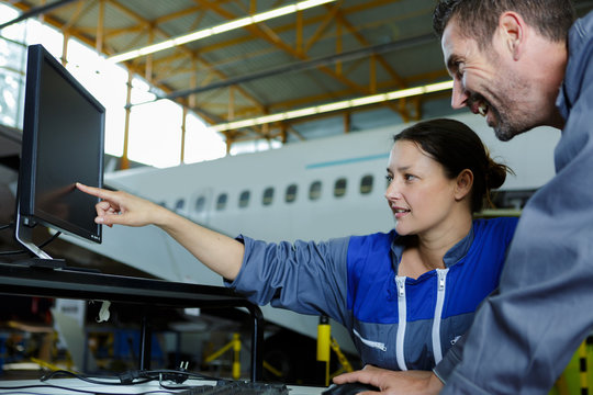 female aircraft mechanic pointing at laptop