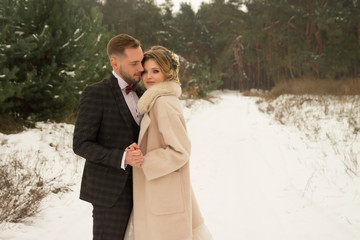 the couple is hugging and close to the kiss, holding hands, a bouquet in their hands. A suit with a butterfly and a coat with a dress. The bride and the groom