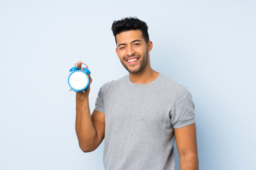 Young handsome man over isolated background holding vintage alarm clock