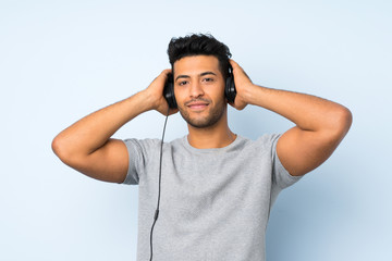 Fototapeta na wymiar Young handsome man over isolated background using the mobile with headphones