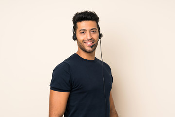 Young handsome man over isolated background working with headset
