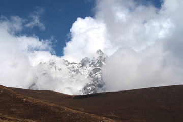 Kyajo Ri mountain peak is visible through dense white clouds in Himalayas in Sagarmatha national park in Nepal near Lunden village. On the way to Everest base camp through Gokyo lakes.