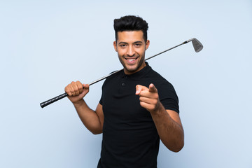 Handsome young man playing golf over isolated blue background points finger at you with a confident...