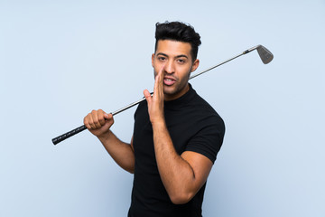 Handsome young man playing golf over isolated blue background whispering something