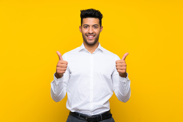 Young handsome man over isolated yellow background giving a thumbs up gesture