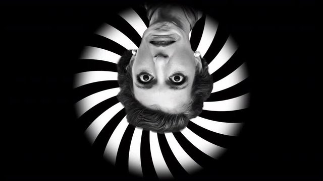 A weird, fast rotating collage: an astonished lady (old-style makeup and hair) moving clockwise, over an hypnotic spiral going counterclockwise. Black-and-white.