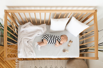 Top view of adorable newborn baby sleeping in wooden crib