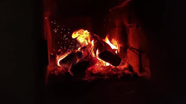 Wood burning in a wood-burning stove. The sparks flew to the sides. Slow motion video. Heating of houses in winter.