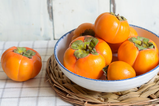 ripe persimmon fruit, isolated on white wooden background
