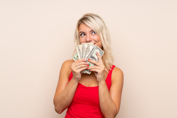 Young blonde woman over isolated background taking a lot of money