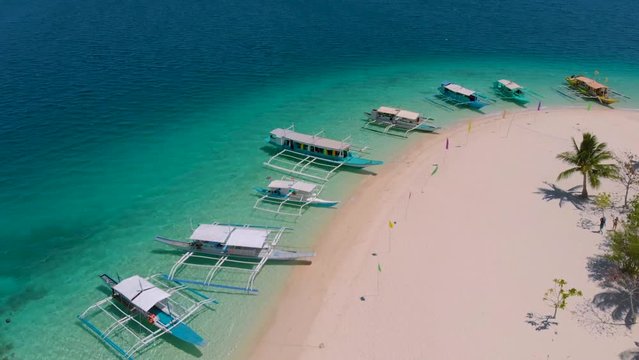 Cinematic Drone movement upon parking tourist boats at the white sand on Pass Island in Coron, Palawan, Philippines