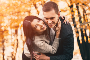 Beautiful young couple hugging in autumn park.