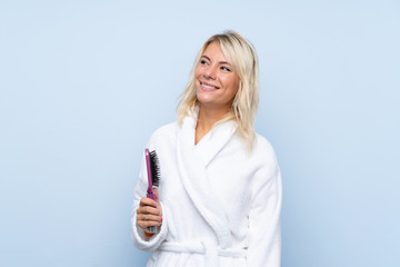 Young woman in a bathrobe with hair comb looking up while smiling