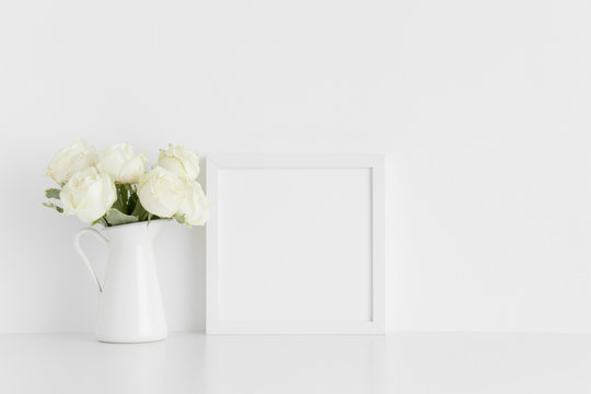 White square frame mockup with a bouquet of white roses in a vase on a white table.