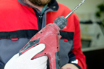in the hands of the installer worker perforator red with traces of scratches and scuffs