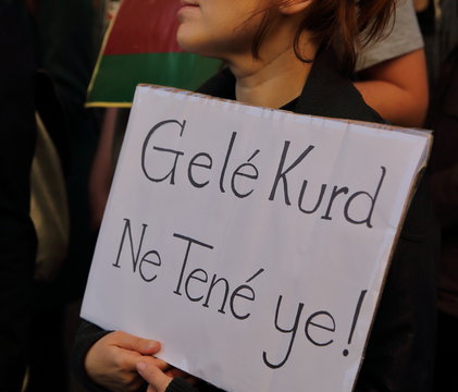 Young girl holds board with slogan in Kurdish language during street demonstration against Turkish invasion in northern Syria