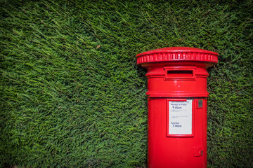 Classic Red British Pillar Box Against Hedge