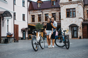 Young husband and wife ride bicycles around the city