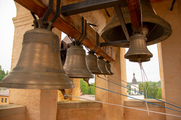 Bells of various sizes hang from a thick wooden beam.