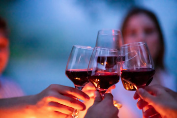 friends toasting red wine glass during french dinner party outdoor