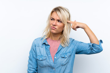 Young blonde woman over isolated white background making the gesture of madness putting finger on...