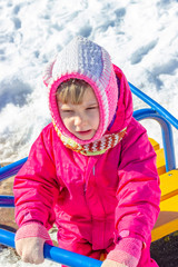 winter, cold. little girl in a pink jacket plays on the street. holds swing and gets angry.