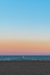 Naklejka na ściany i meble Boat in the sea seen from the shore at sunset