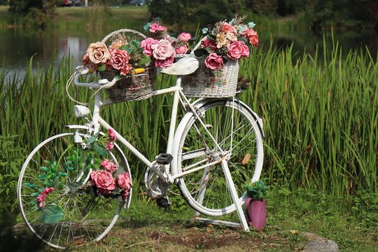 street decor, a white bicycle with baskets of flowers on it