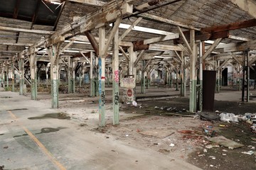 old large abandoned cluttered industrial room with beams, graffiti painted walls