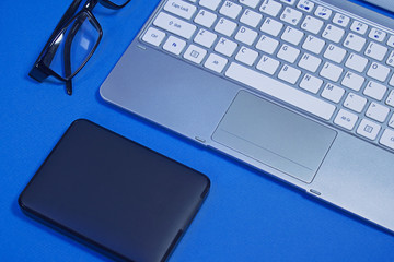 Fototapeta premium A portable hard drive and a laptop. Business mockup with blue background