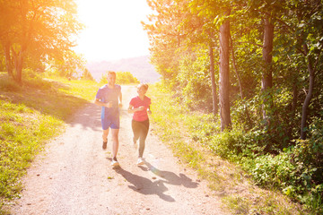 young couple jogging on sunny day at nature